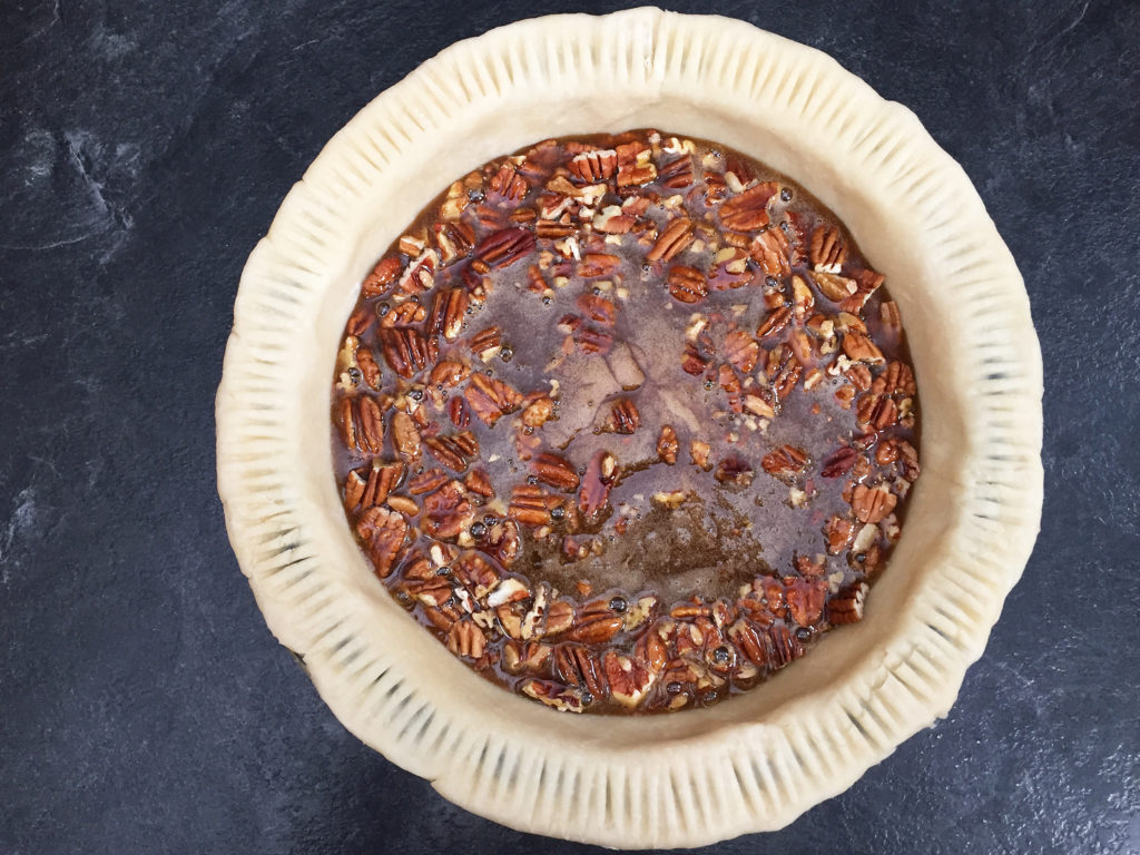 pouring filling into pecan pie crust