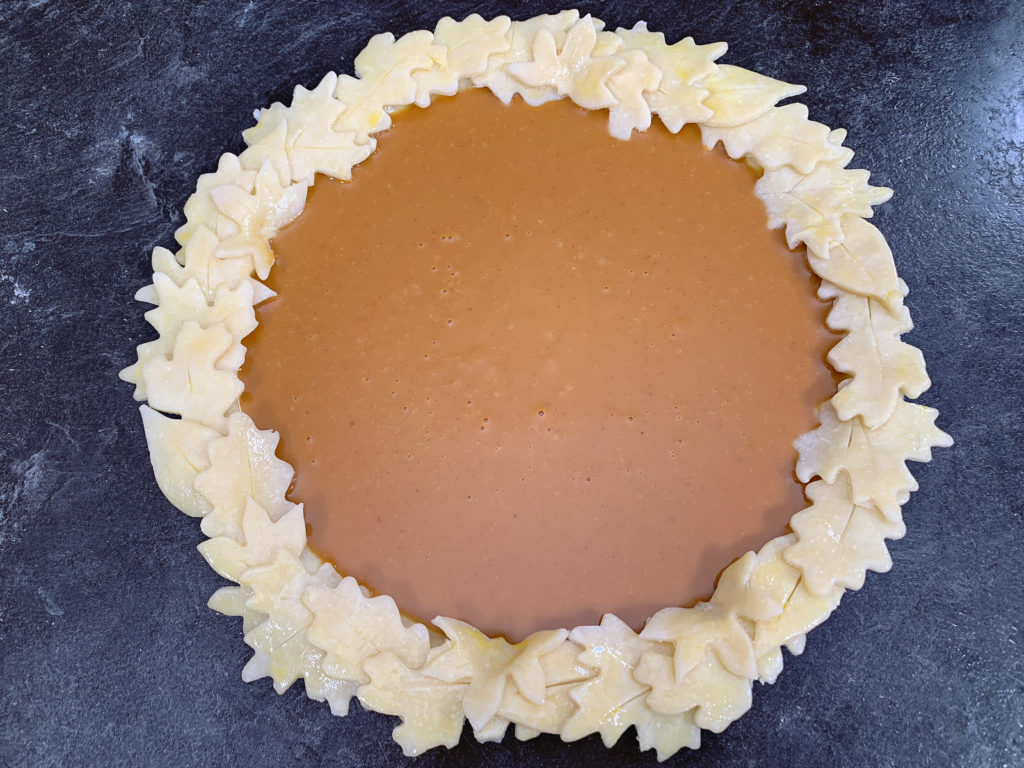 unbaked pumpkin pie with leaf cut outs on crust