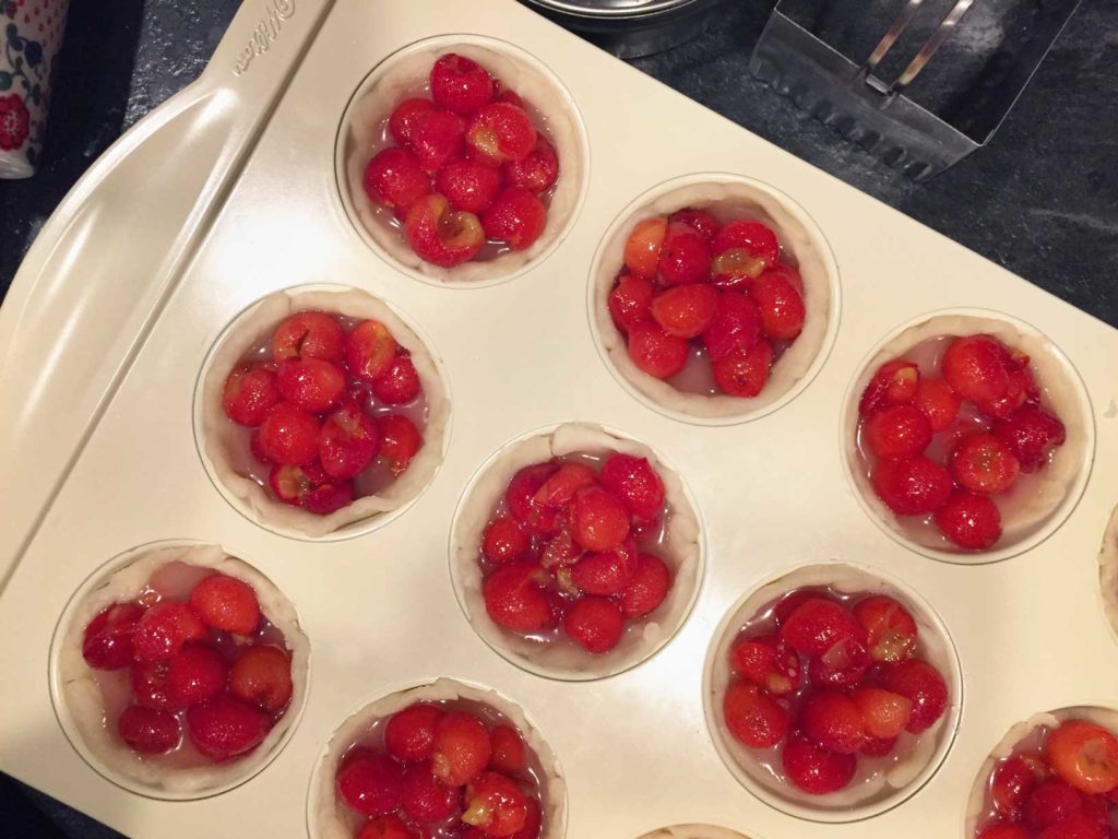 Close up of cherry pie filling in muffin tin cups