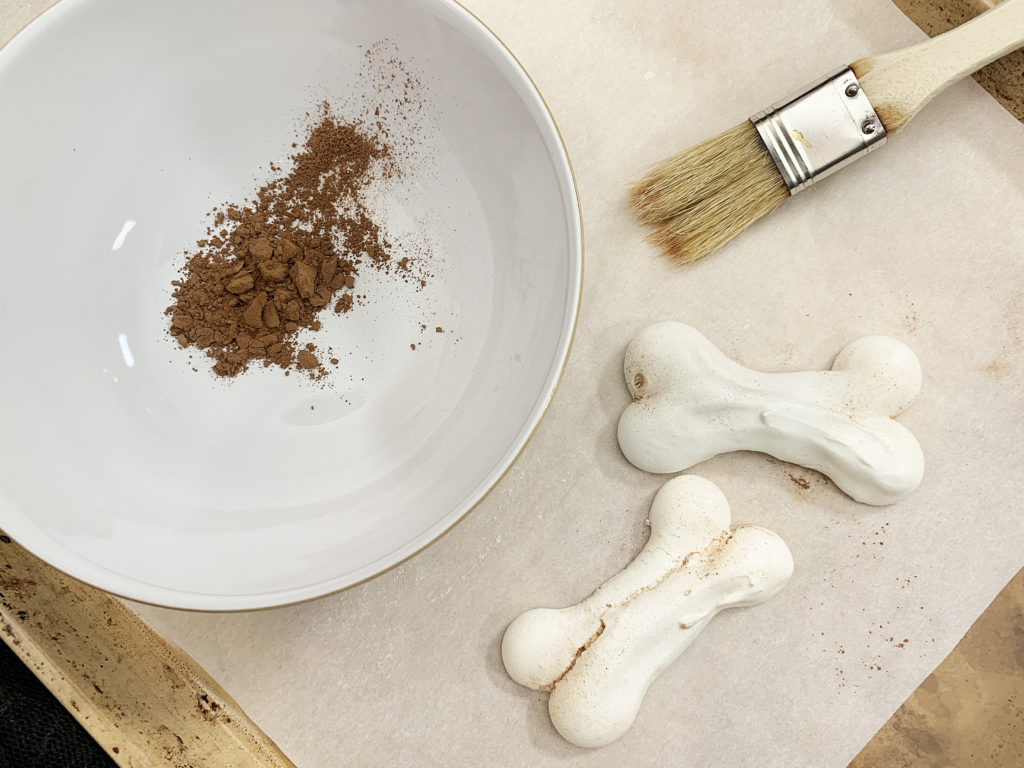 brushing meringue bones with cocoa powder