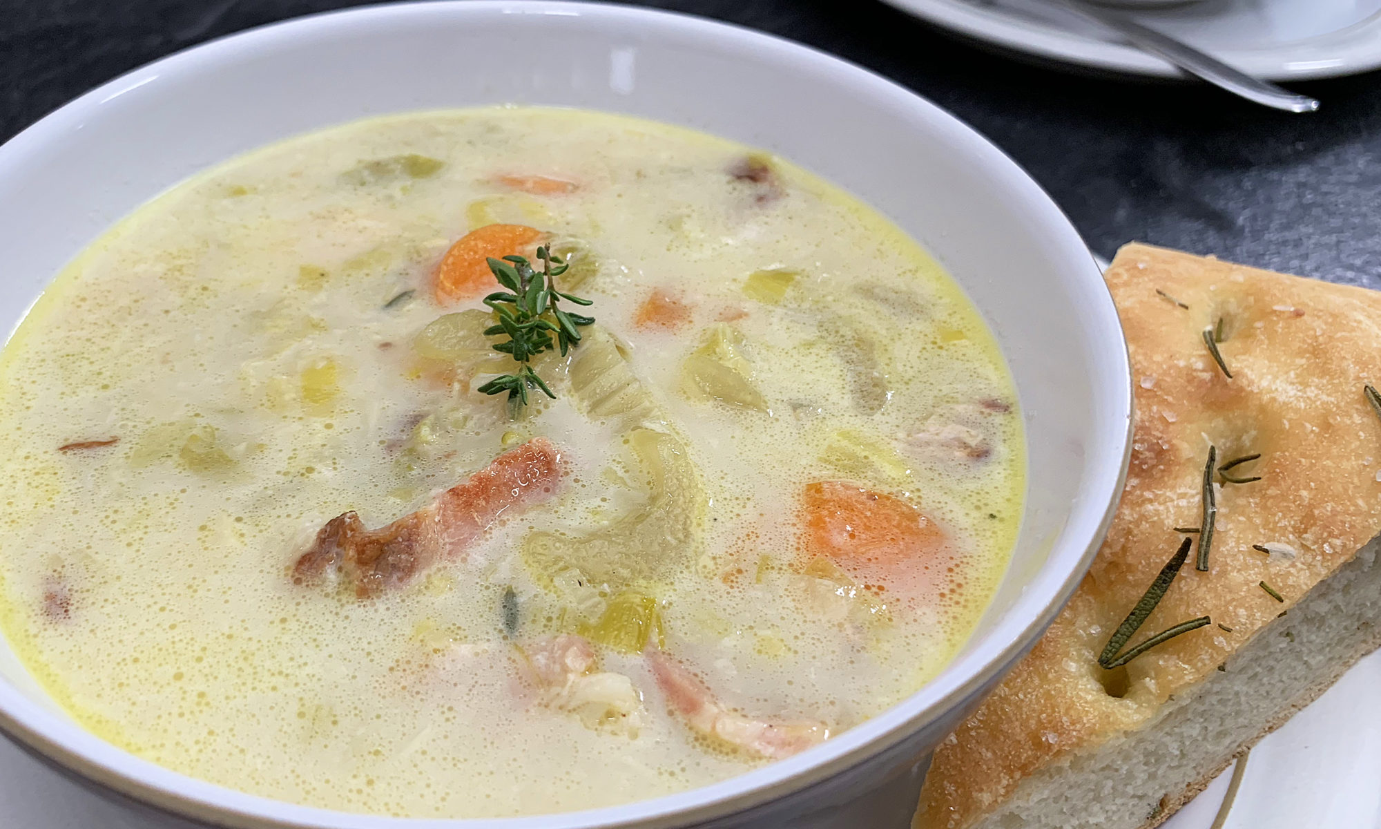 bowl of creamy potato bacon leek soup with focaccia bread