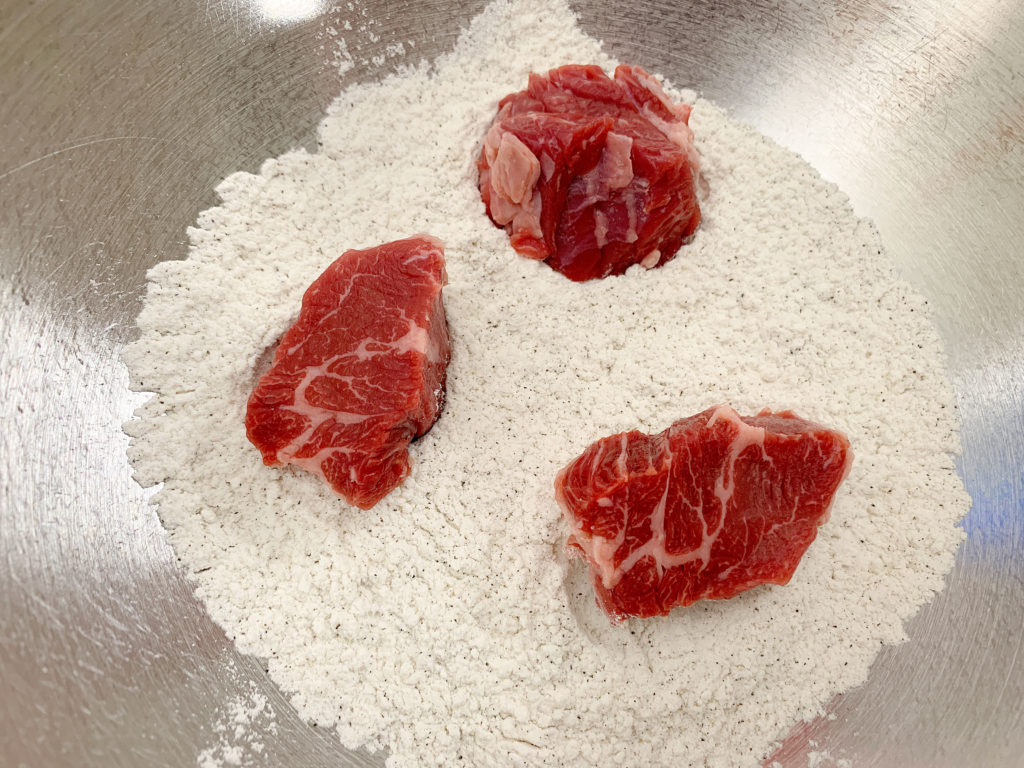 beef cubes in bowl of flour