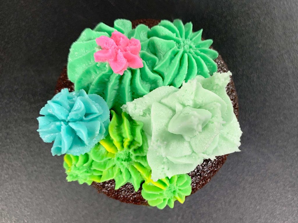 piping a flower onto the top of a buttercream cactus