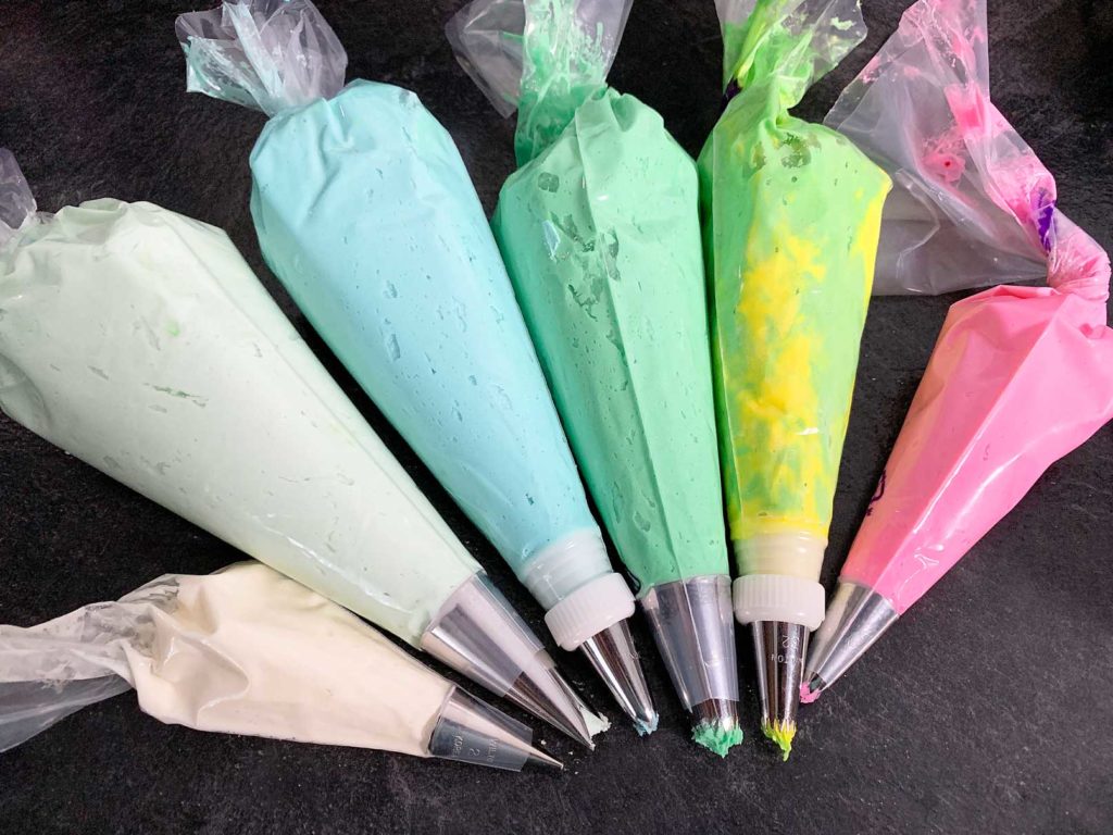 piping bags filled with buttercream in assorted colours