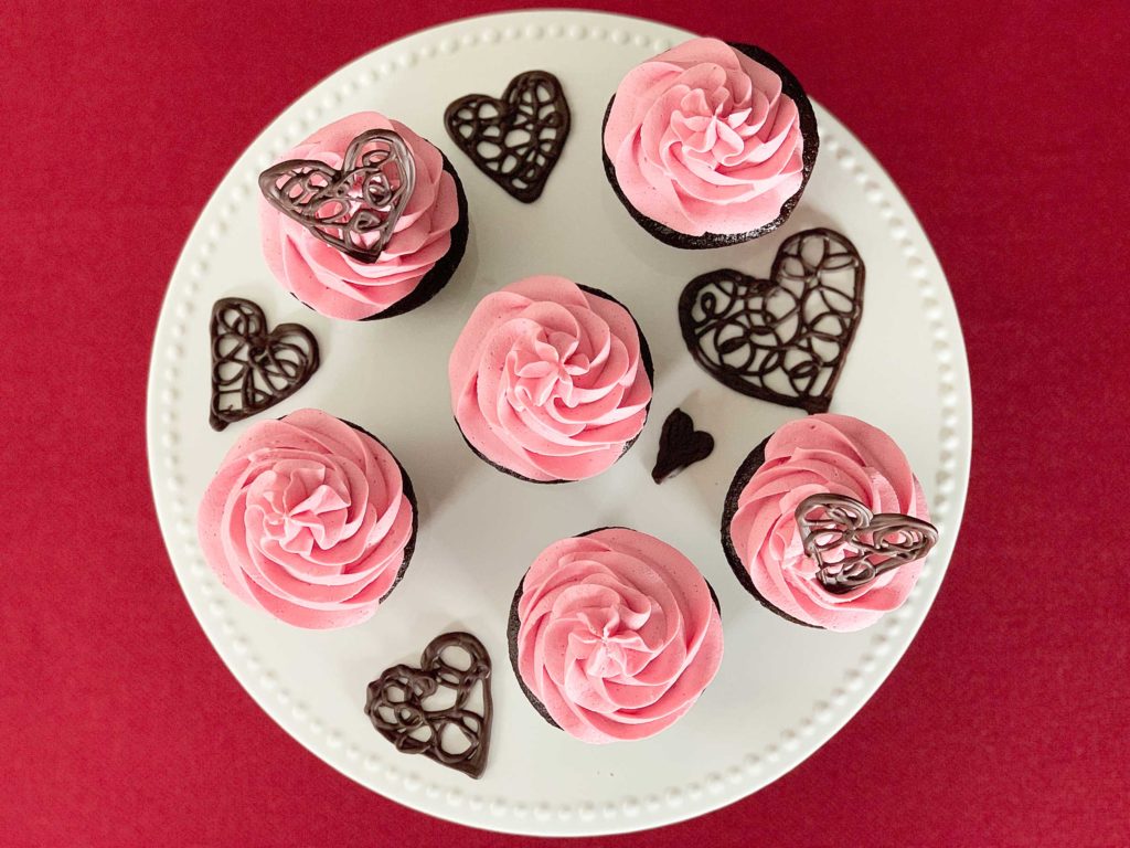 Birds eye view of cupcakes on a cake stand surrounded by decorative chocolate hearts