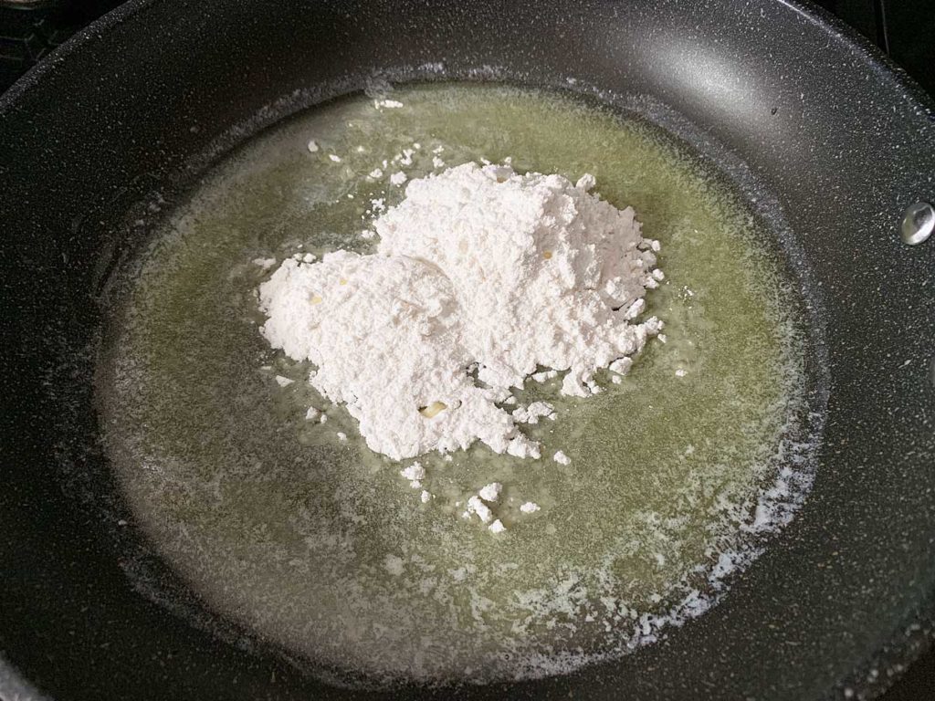 adding flour to the melted butter to make a roux