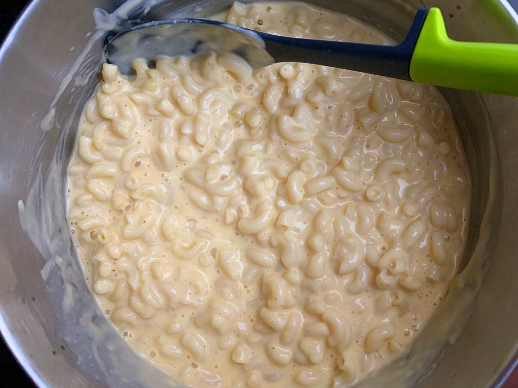stirring the cheese sauce into the macaroni pasta