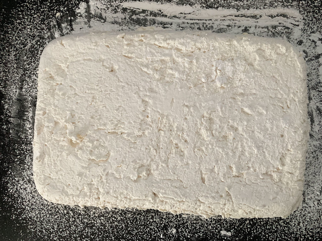 Overhead shot of sheet of marshmallows, flipped out of pan onto a cutting board