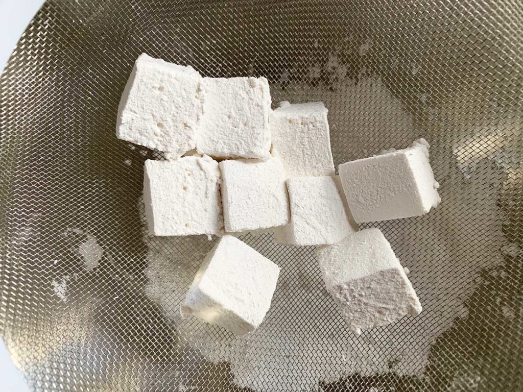 Dusting marshmallow squares with icing sugar