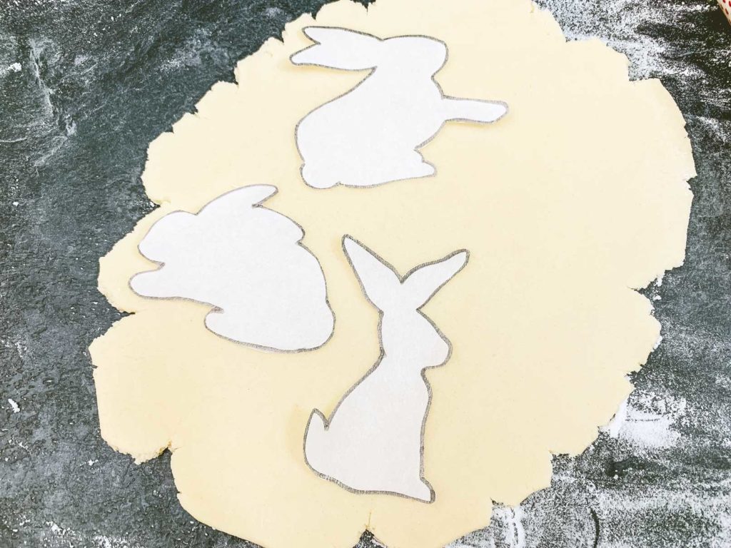 parchment paper cut outs placed on top of rolled out sugar cookie dough