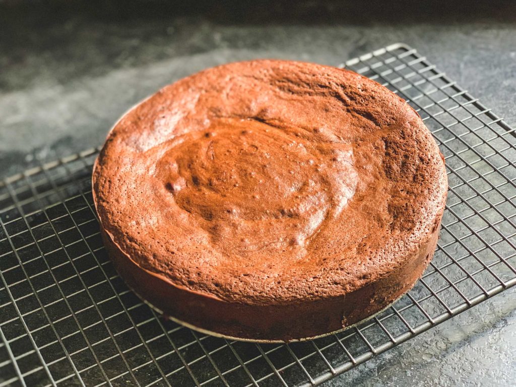 side angle of flourless chocolate cake on a cooling rack