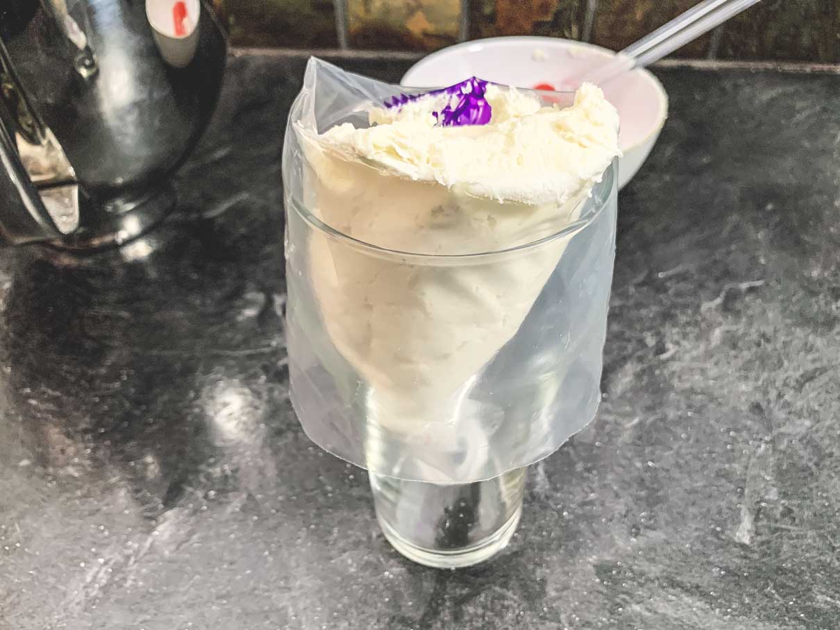 piping bag filled with frosting, standing upright in a glass