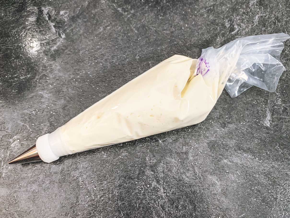 piping bag, filled with frosting, with the end twisted closed