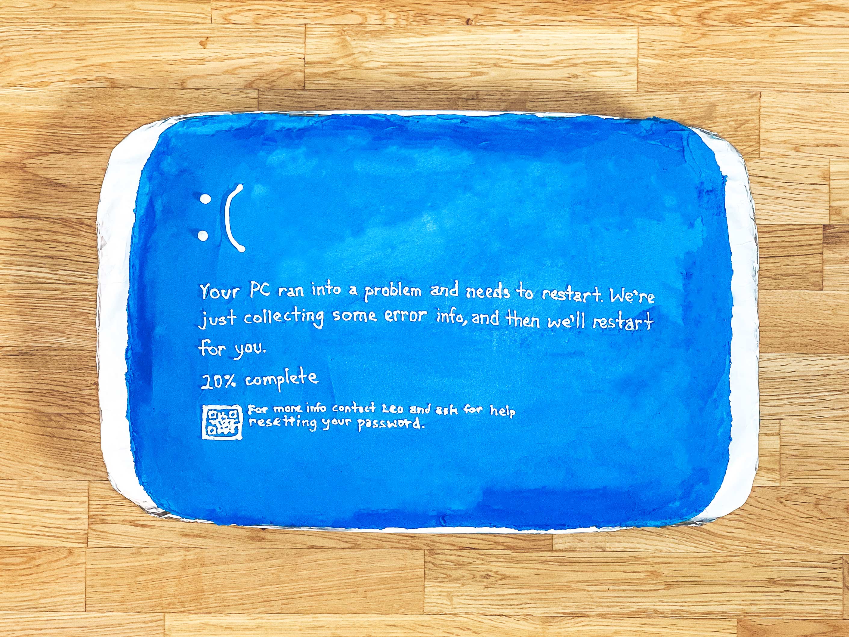 blue cake with a sad face and writing on it saying "Your PC ran into a problem and needs to restart. We're just collecting some error info, and then we'll restart for you. 20% complete."