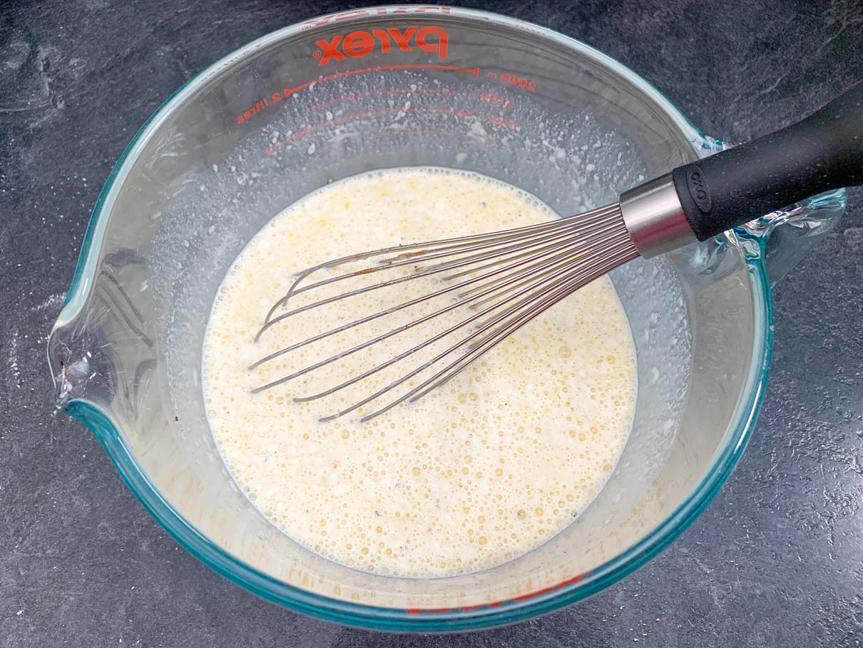 whisking eggs, cream and seasoning together in bowl