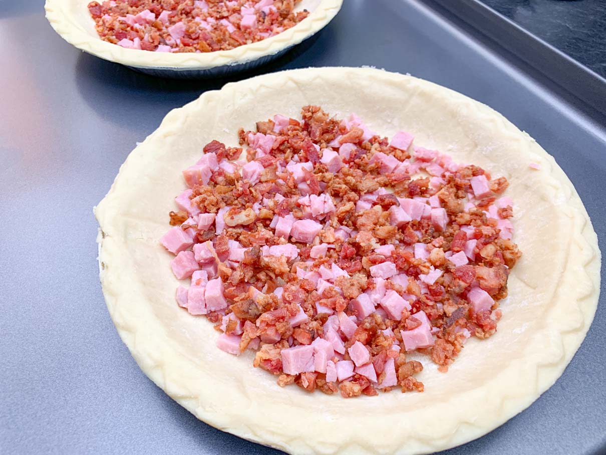 ham and bacon sprinkled on bottom of pie shell
