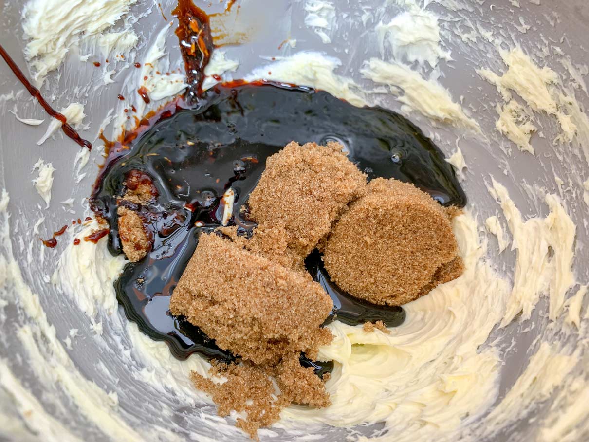 molasses and brown sugar on top of butter in mixing bowl