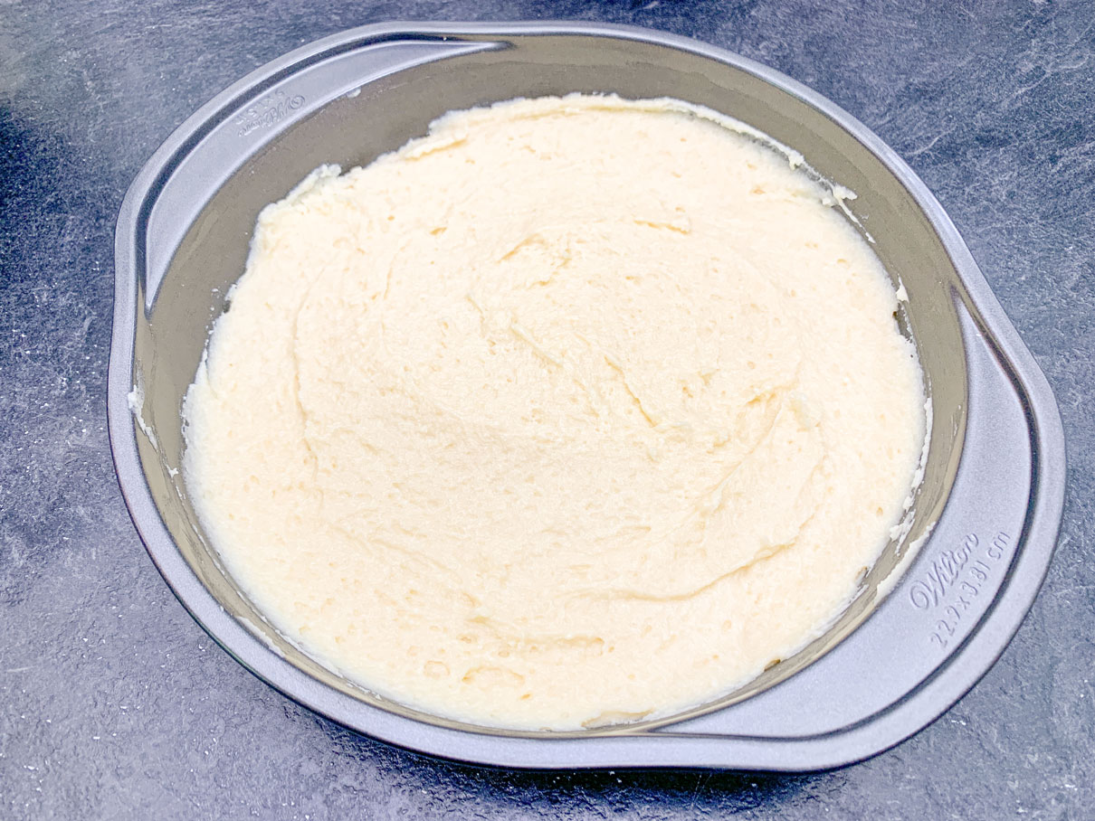 peach ricotta cake batter spread evenly in round cake pan