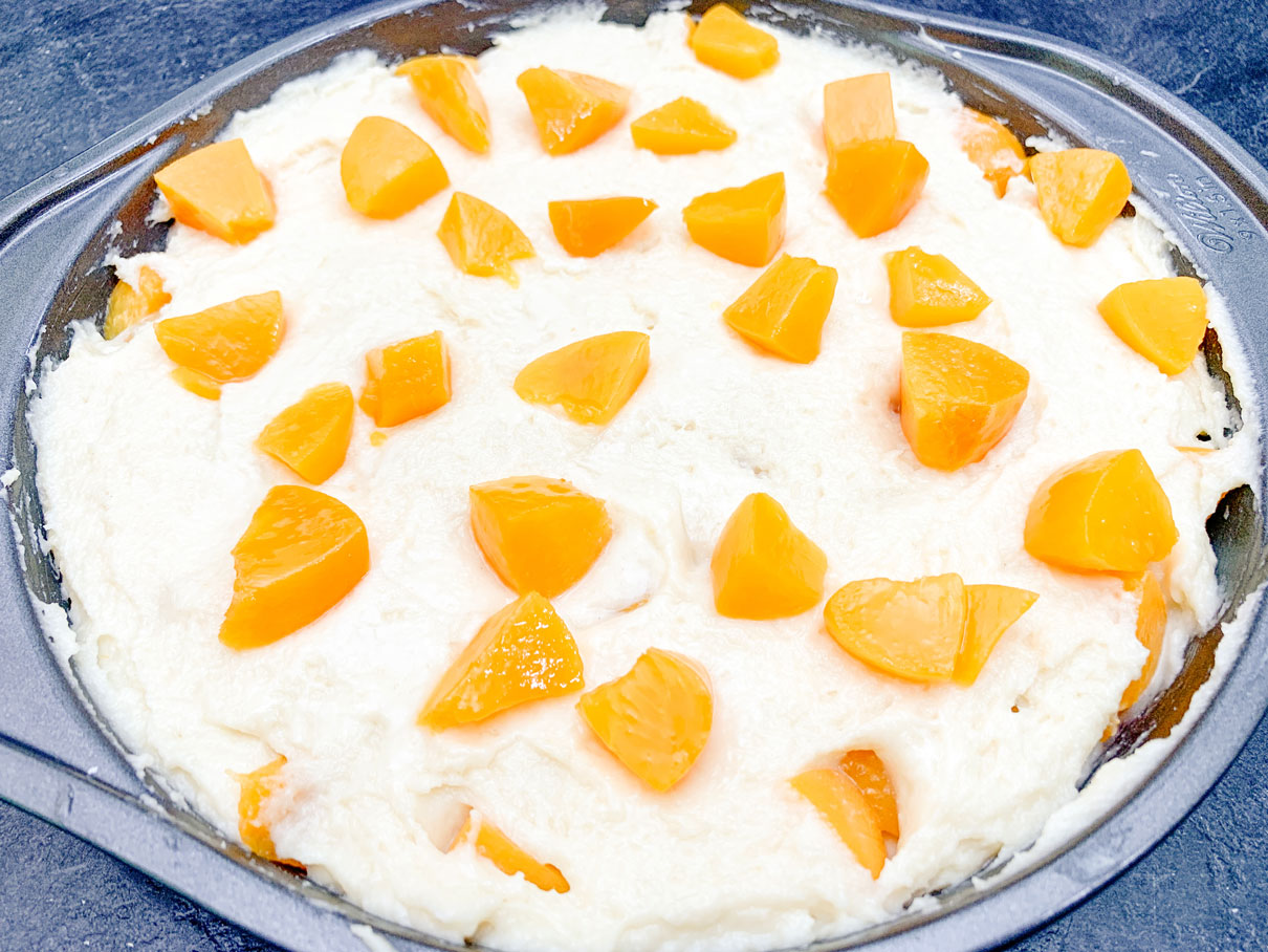 close up of chopped up peaches on top of cake batter (second layer of peaches)