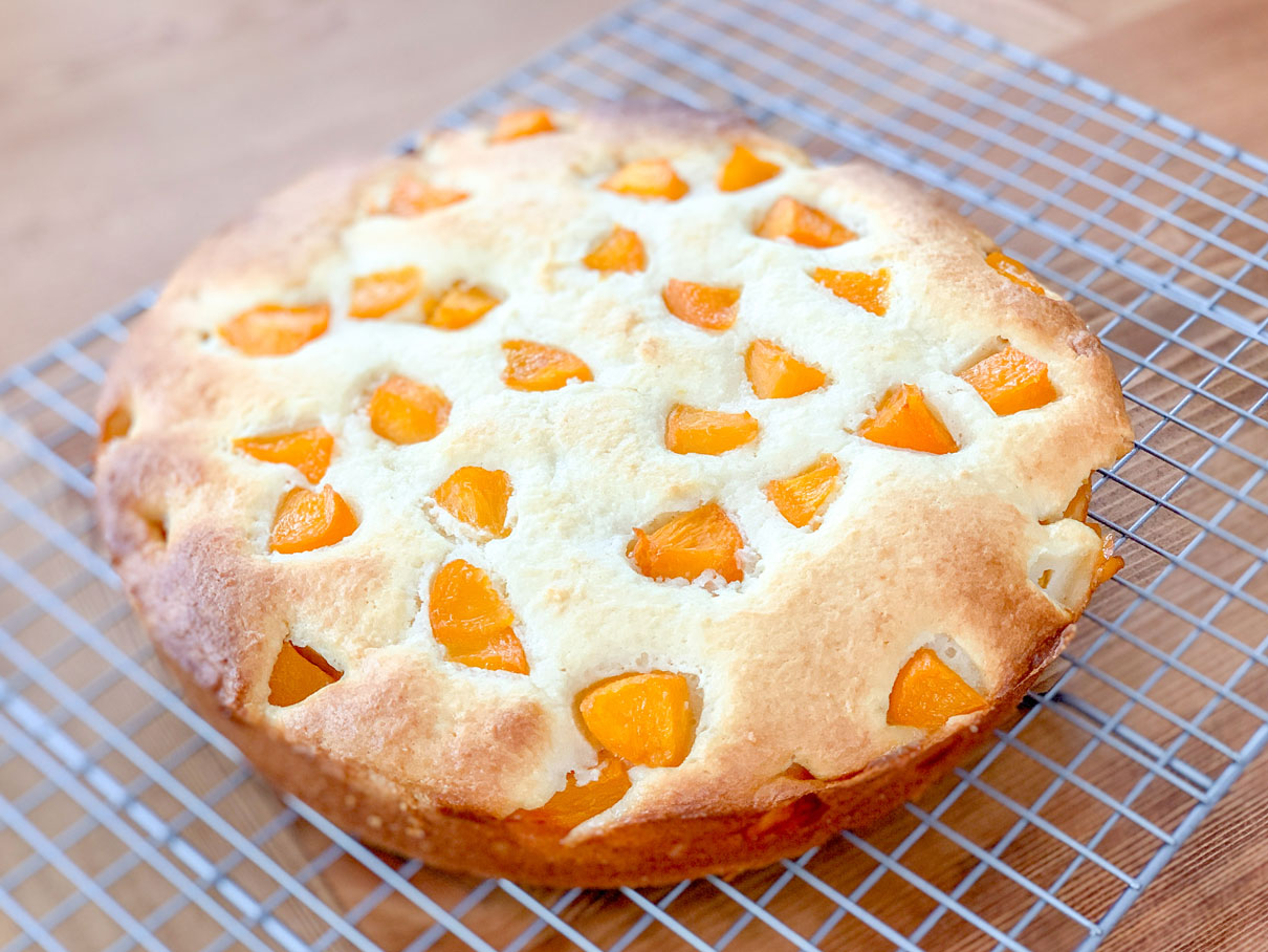 peach ricotta cake cooling on a wire rack
