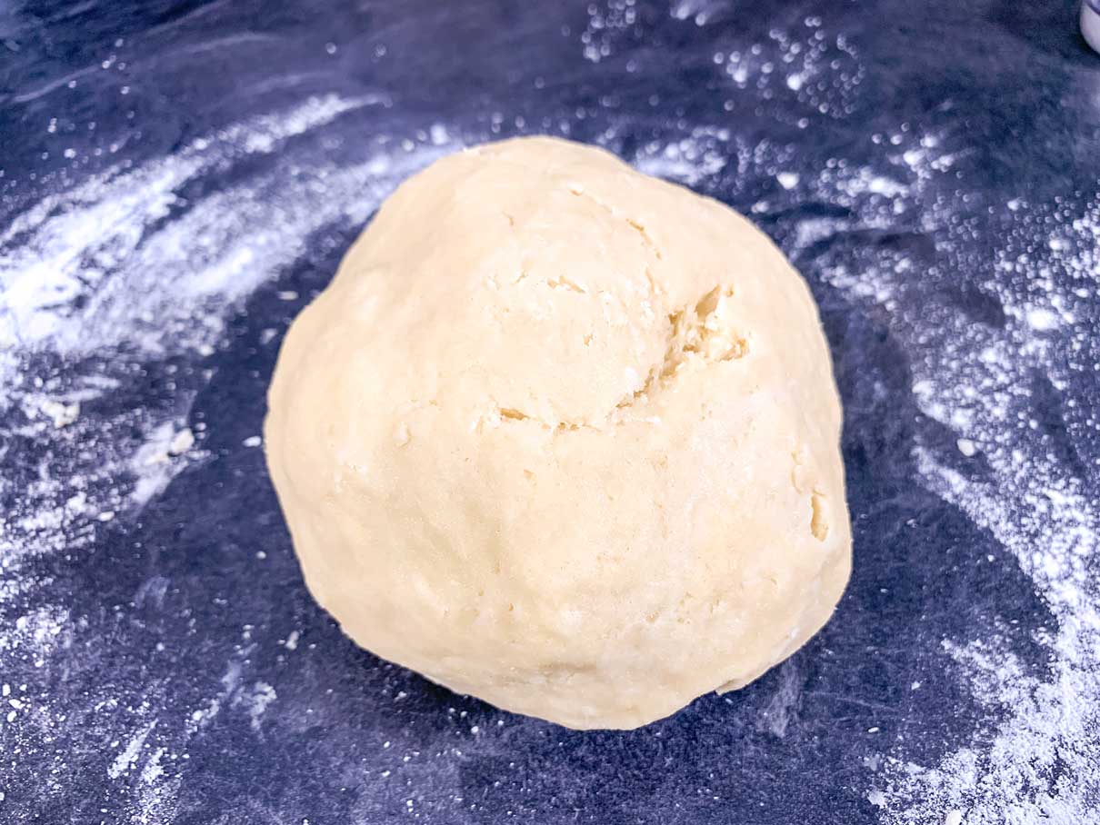 kneaded ball of dough sitting on a lightly floured surface