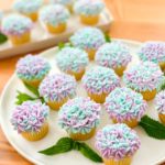 Mini hydrangea cupcakes on a round plate, accented with mint leaves