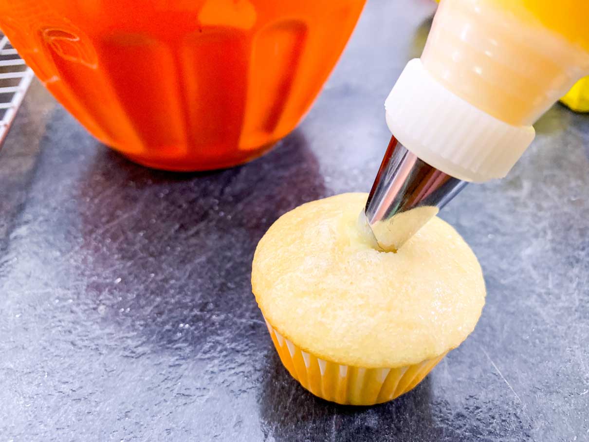 Poking the piping tip into the centre of a cupcake