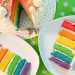 overhead shot of the rainbow cake, with two slices cut out and on plates next to it