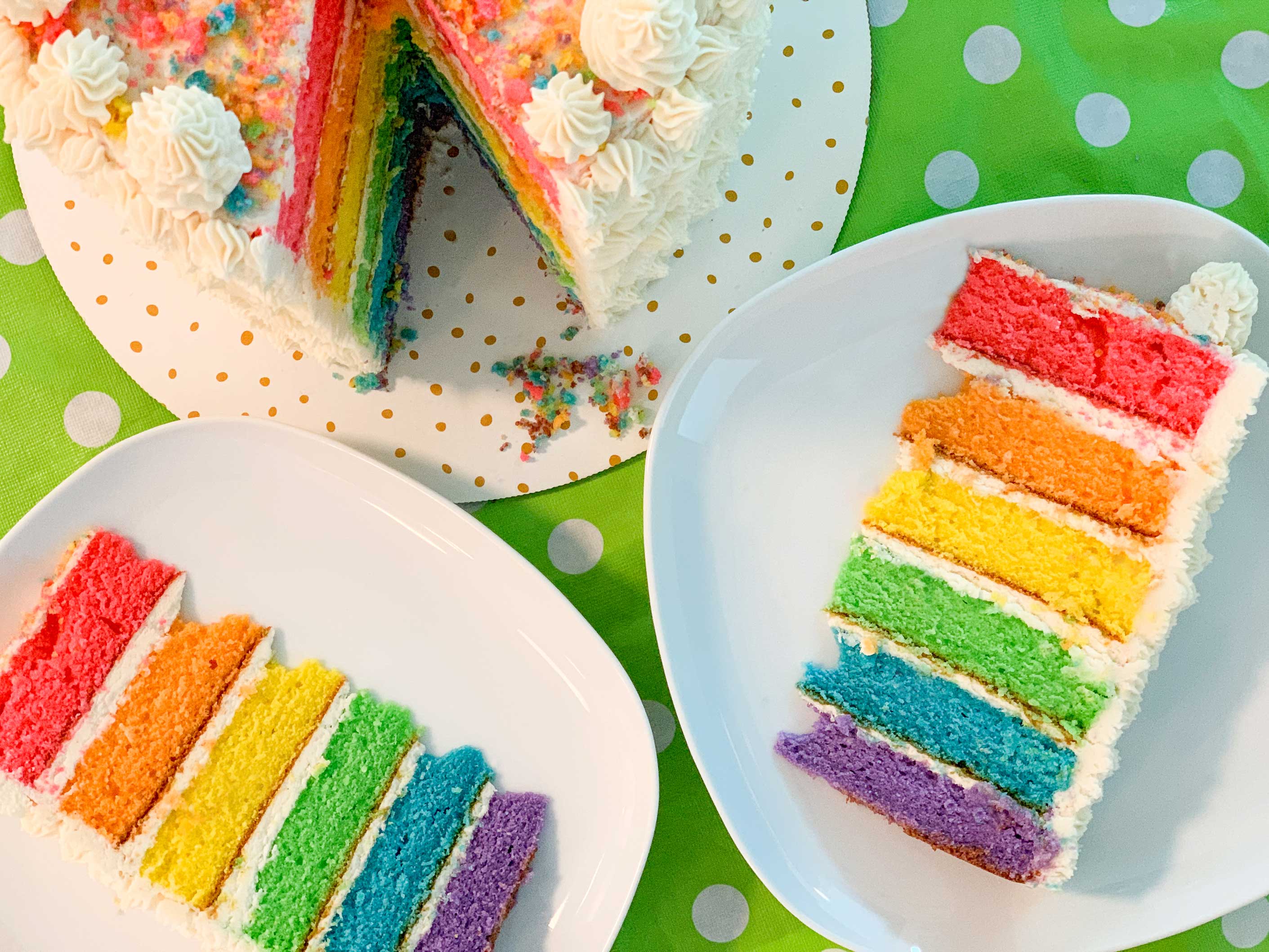 overhead shot of the rainbow cake, with two slices cut out and on plates next to it