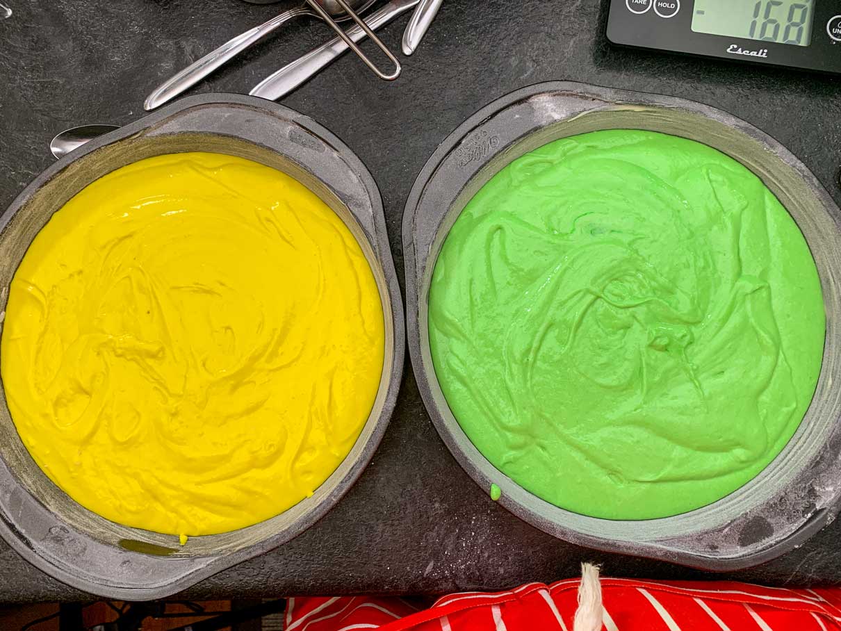 two nine inch round baking pans, one filled with yellow batter, one filled with green batter