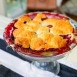 mixed berry cobbler, resting on a cake stand, ready for serving