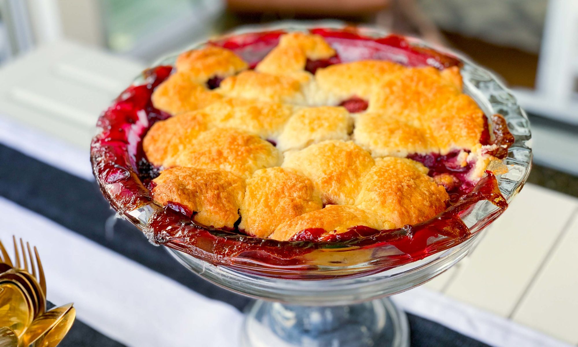 mixed berry cobbler, resting on a cake stand, ready for serving