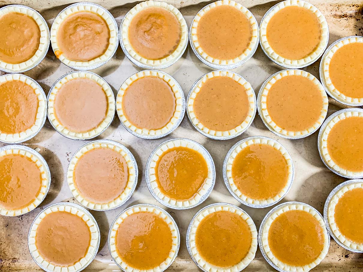 tray of tart shells, filled with pumpkin pie filling