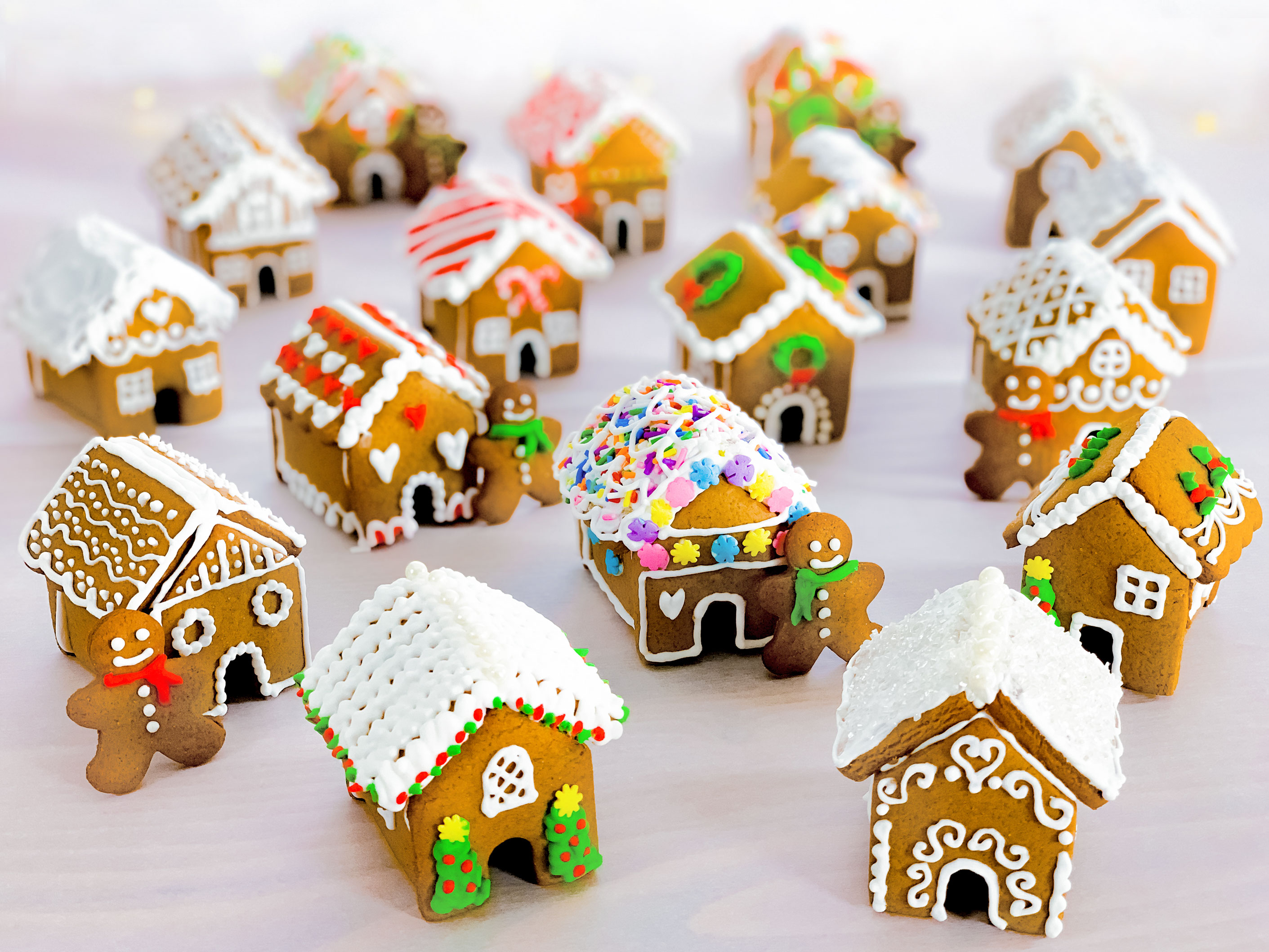  un groupe de mini maisons en pain d'épice après avoir été décorées, avec des mini-hommes en pain d'épice adossés aux maisons 