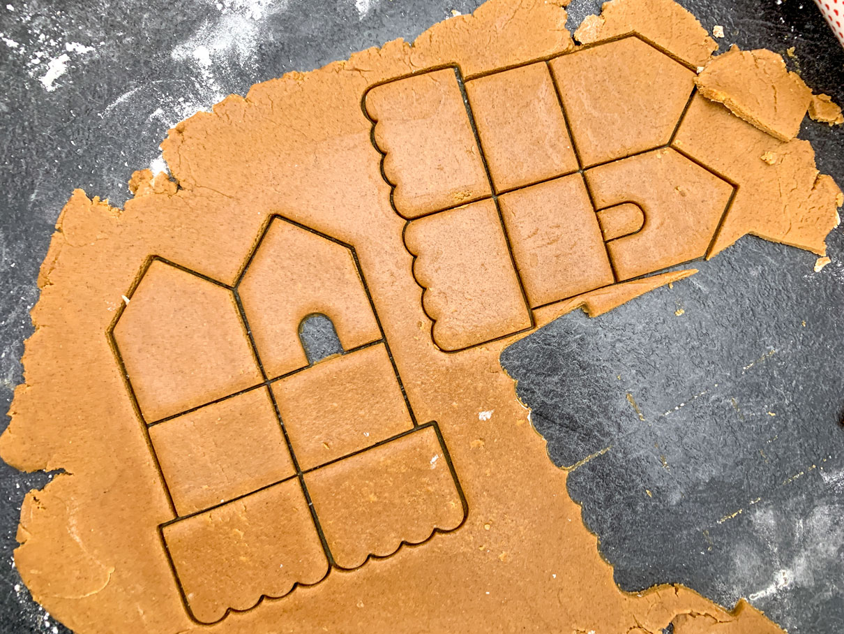 rolled out gingerbread dough, with gingerbread house shapes cut into it