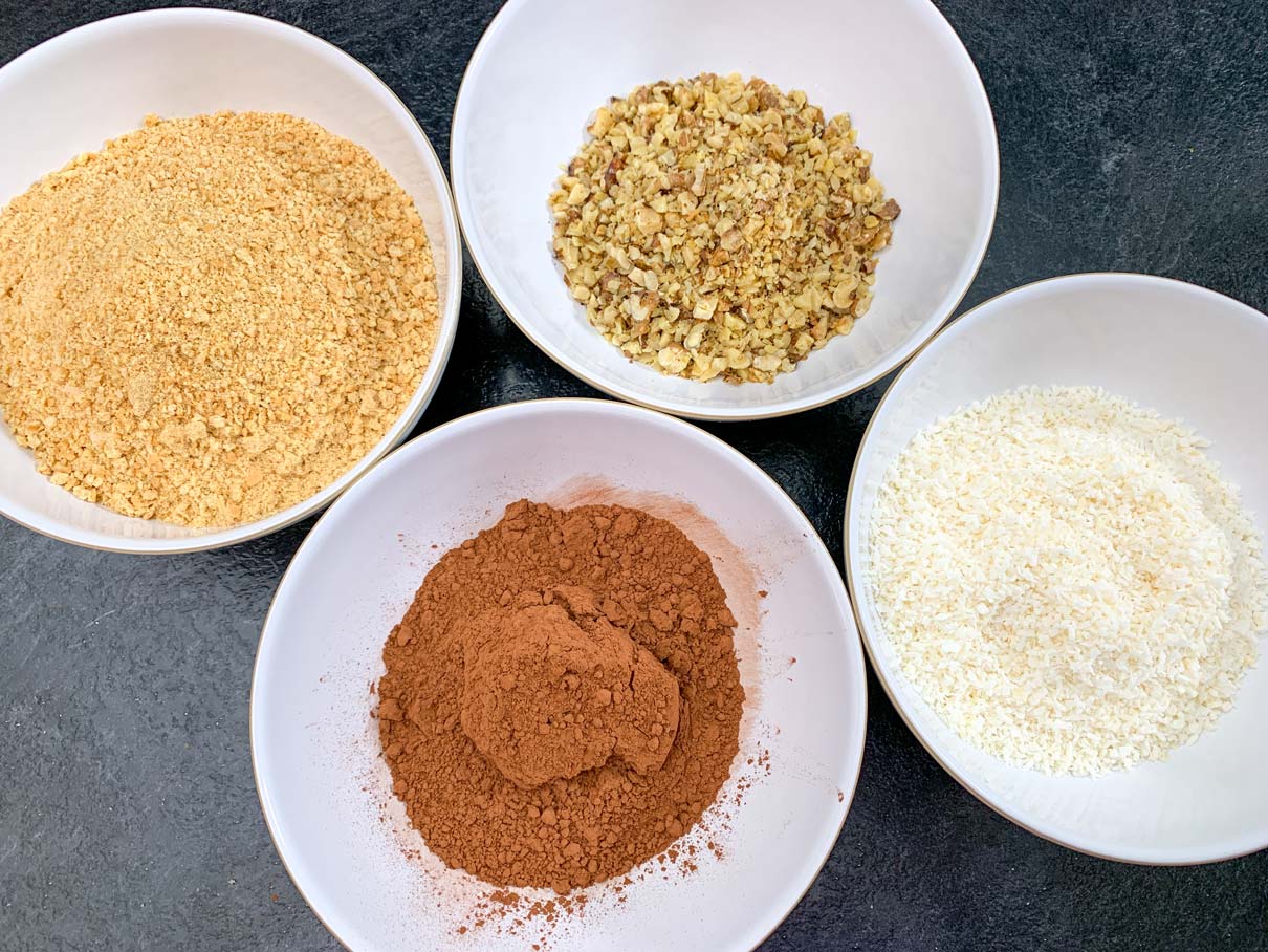 Crushed graham wafers, walnuts, cocoa and coconut, measured out in separate bowls