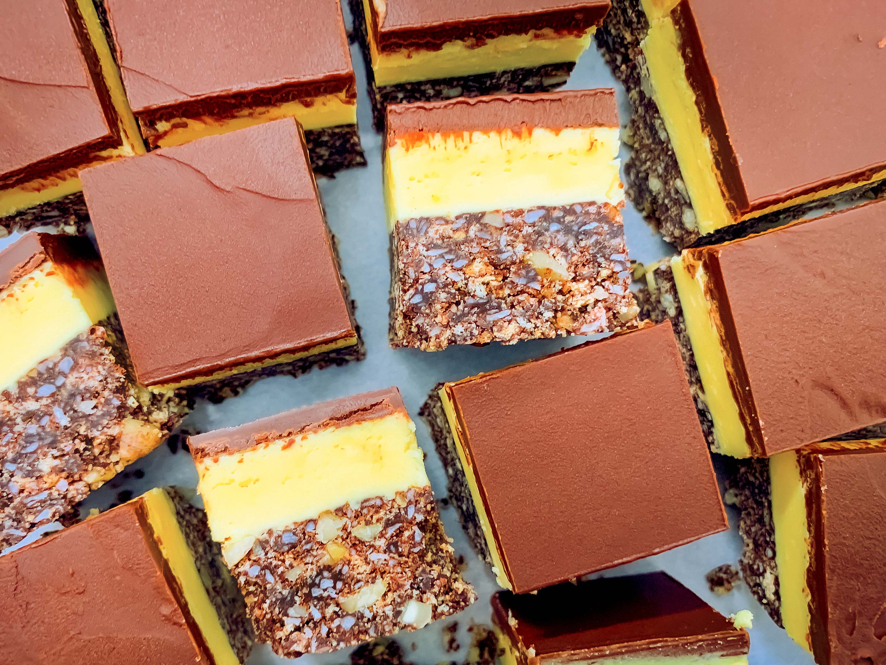 Nanaimo bars all cut up, some facing upwards, some on their sides so you can see the layers