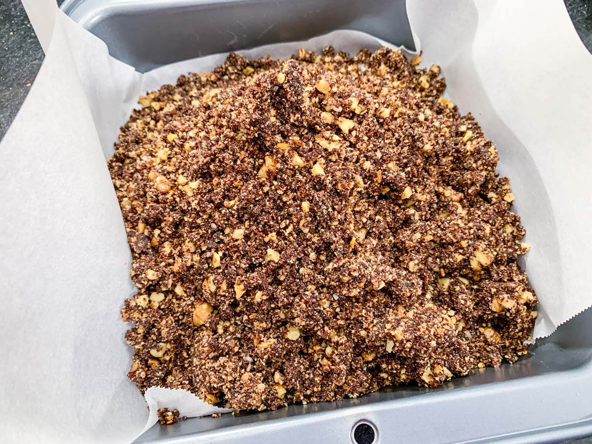 Base layer mixture piled into a prepared 8 inch square baking pan