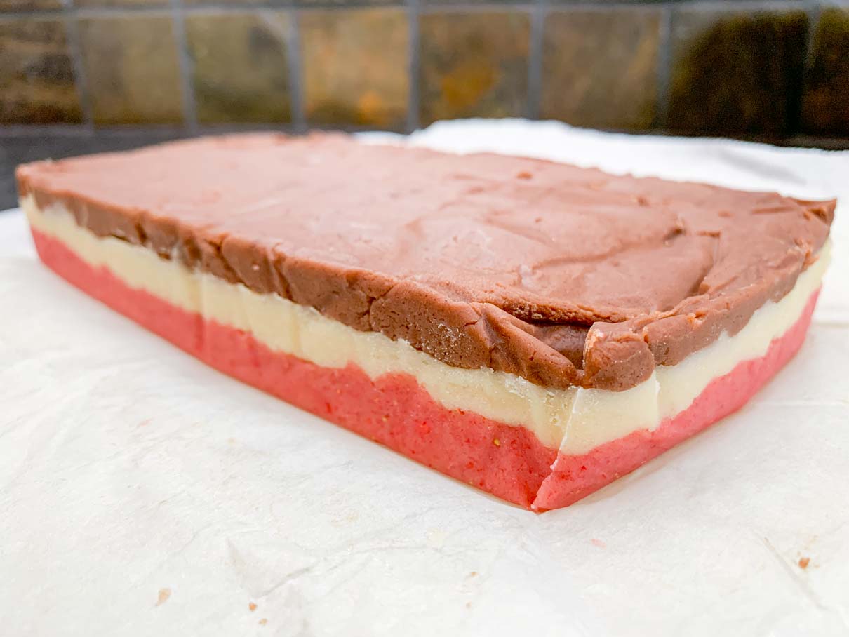 side view of the block of dough after it has been chilled, showing the three different layers of chocolate, vanilla and strawberry
