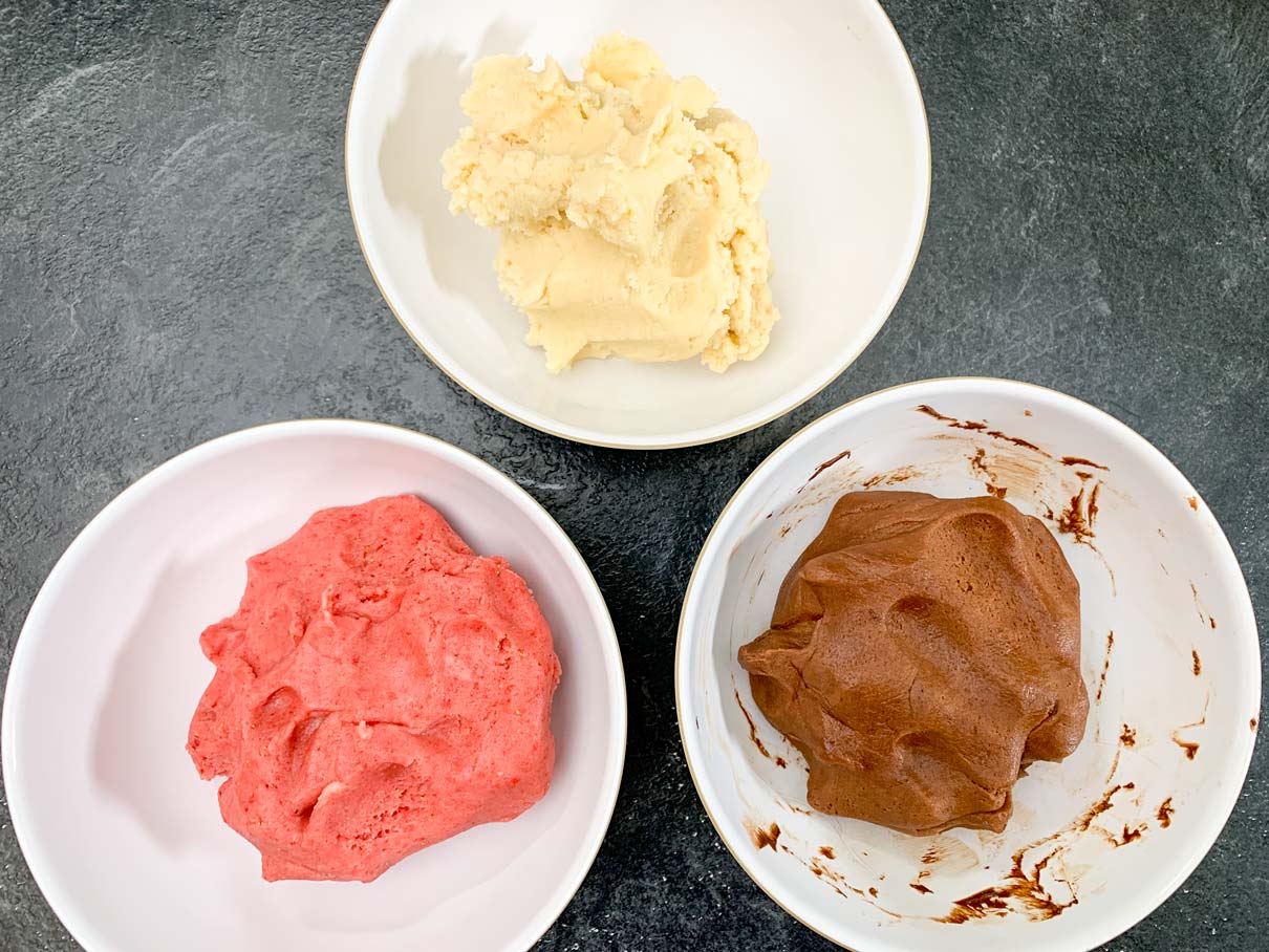 strawberry, vanilla and chocolate dough in three separate bowls on the counter