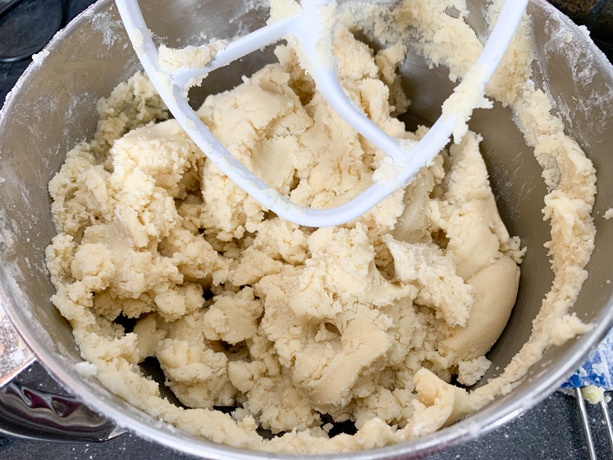 The dough all mixed up in the bowl of a mixer