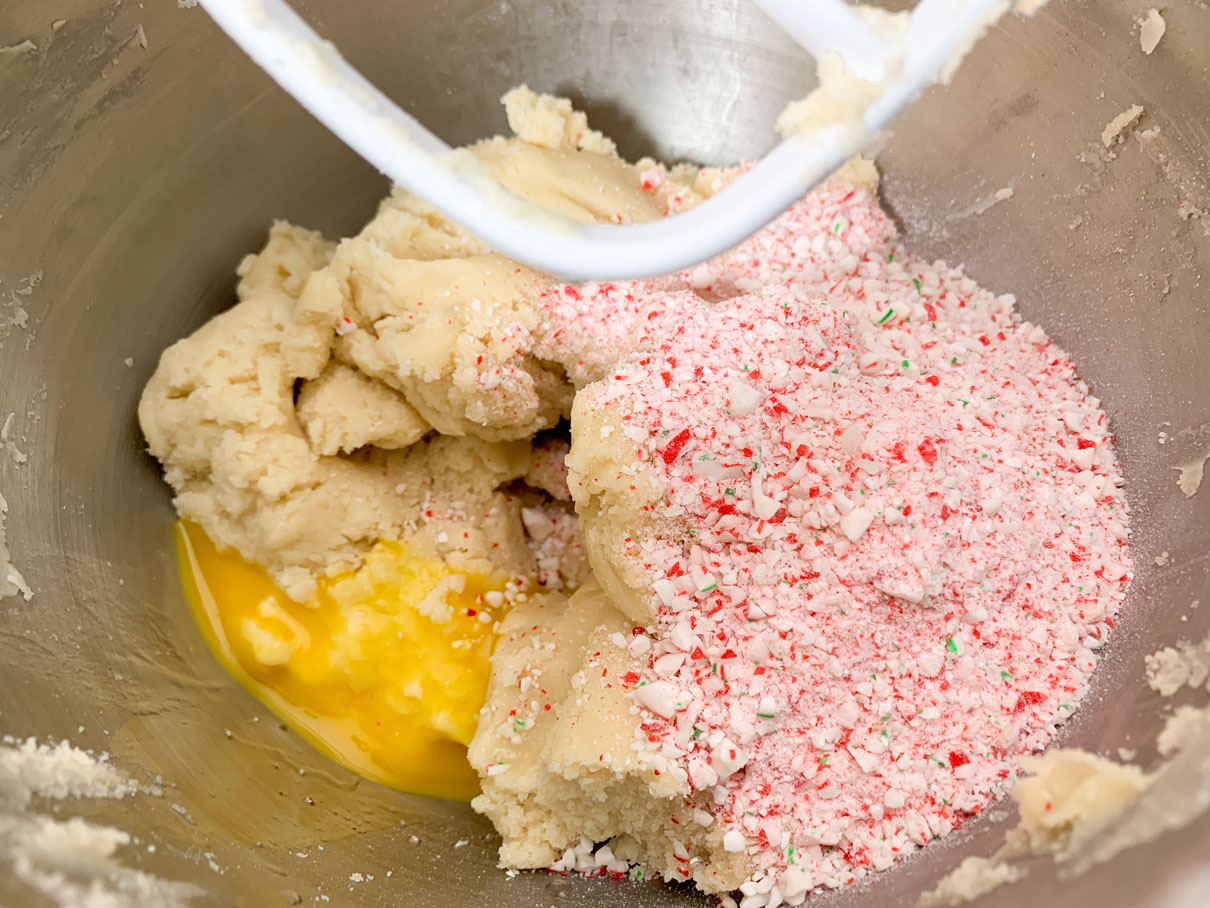 Adding the egg and crushed candy cane to the dough