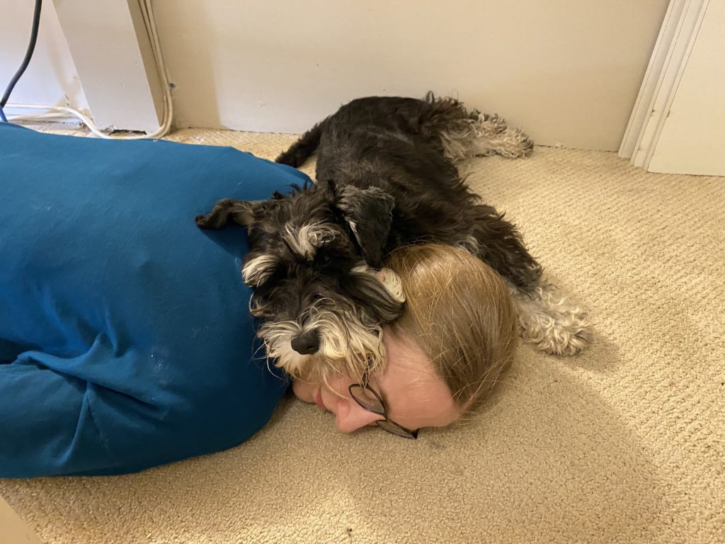 Joan laying on the floor with her dog laying on top of her.