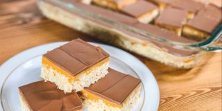 plate of chocolate caramel rice krispies squares on a table with dish of rice krispies in background