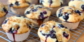 side angle of fresh baked blueberry muffins, cooling on a wire rack