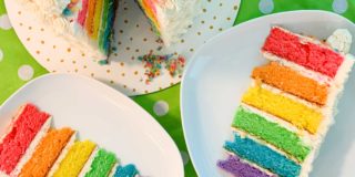 overhead shot of the rainbow cake, with two slices cut out and on plates next to it