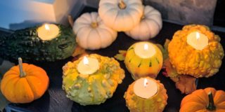 fall gourds with tea lights lit, sitting on the mantle of a fireplace